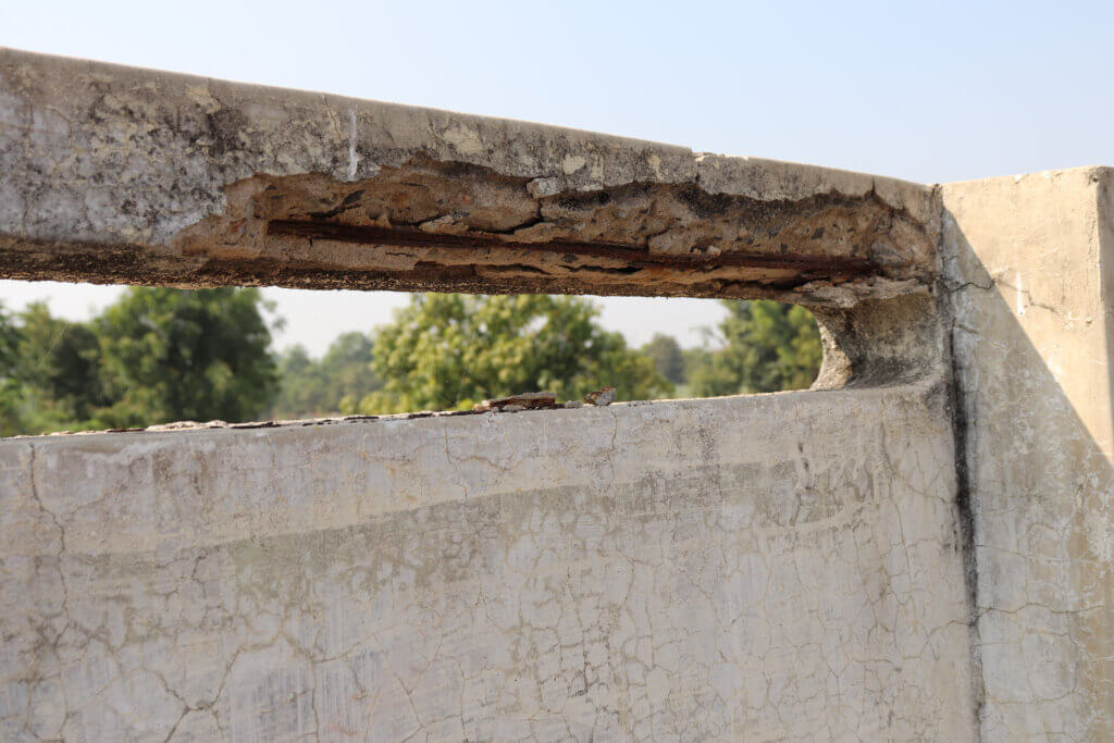 An example of concrete corrosion, showing the top of an outdoor structure with badly damaged concrete surface.